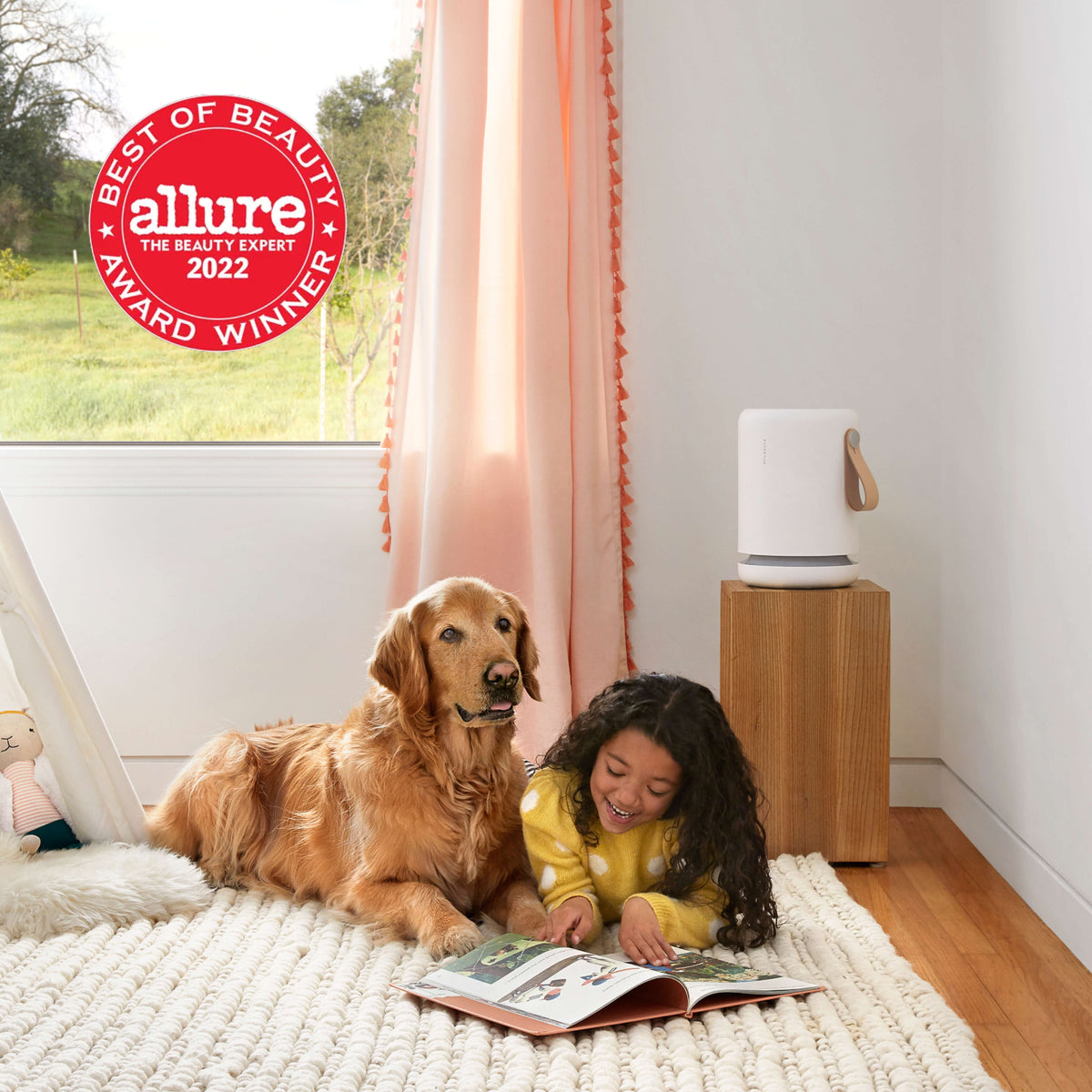 Child and dog laying on the floor reading a picture book in front of an Air Mini+ air purifier
