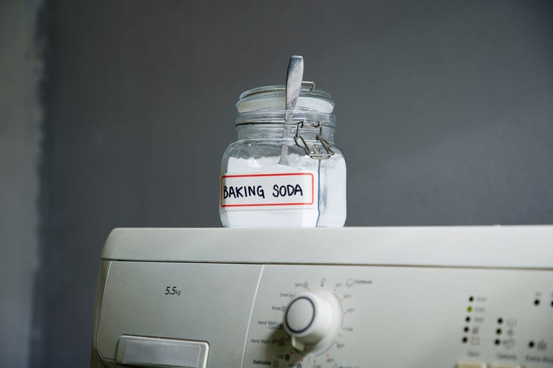 Container of baking soda on top of a washing machine