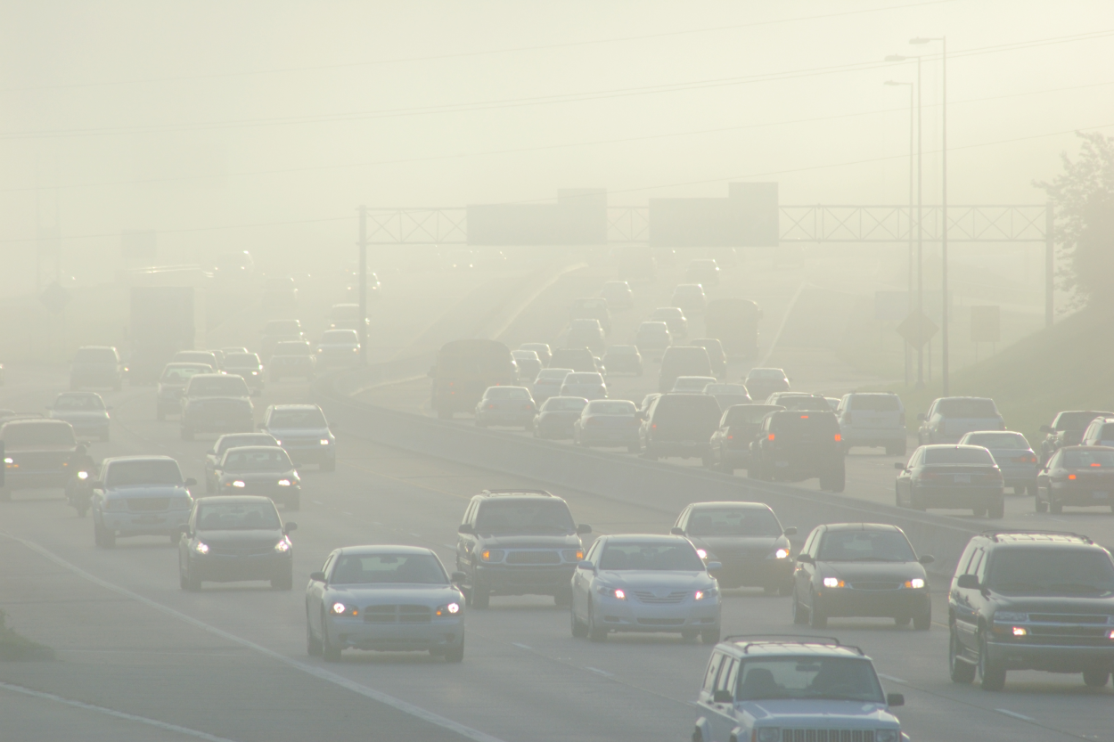 Many cars on the freeway in dense smog