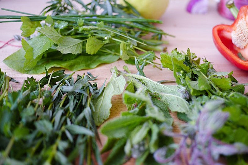 Fresh chopped herbs with red pepper and onion in the background