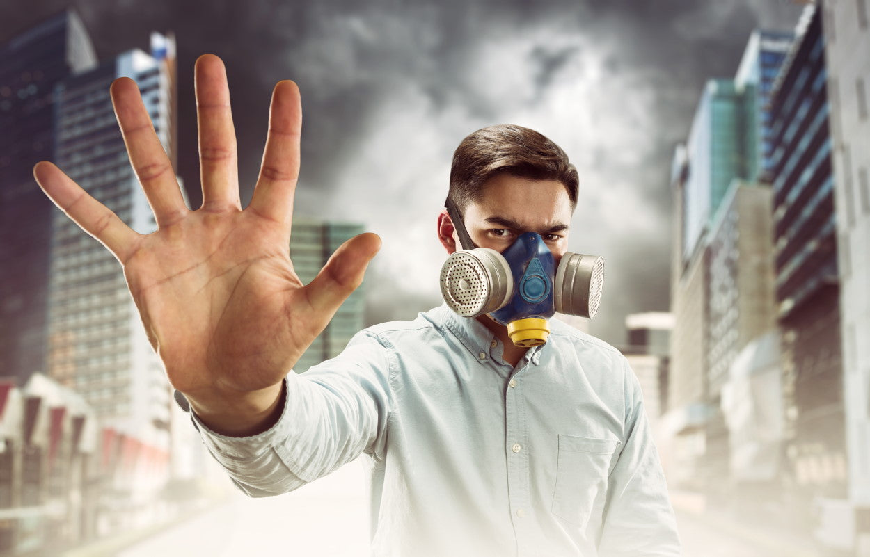 Man wearing a gas mask and holding up his hand