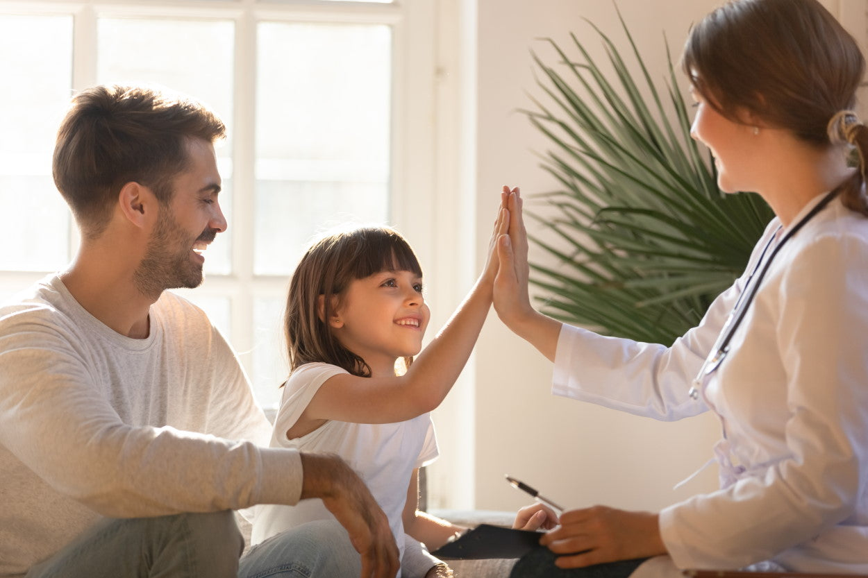 Young girl high-fiving her mother while father watches