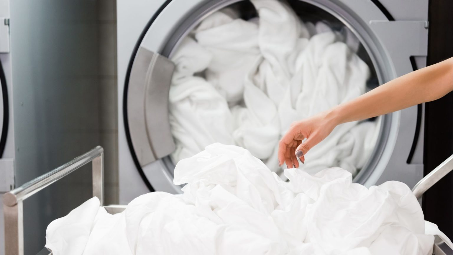 Woman folding white laundry out of the dryer