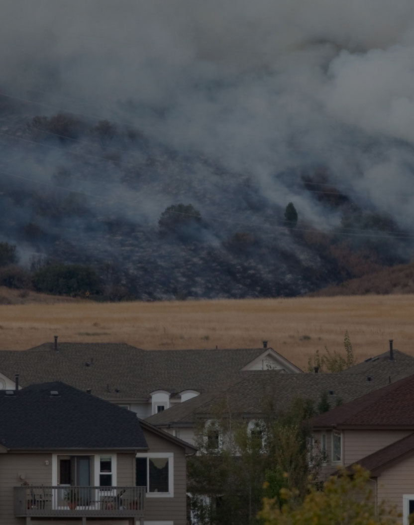 Homes with wildfire smoke covering hills in the background