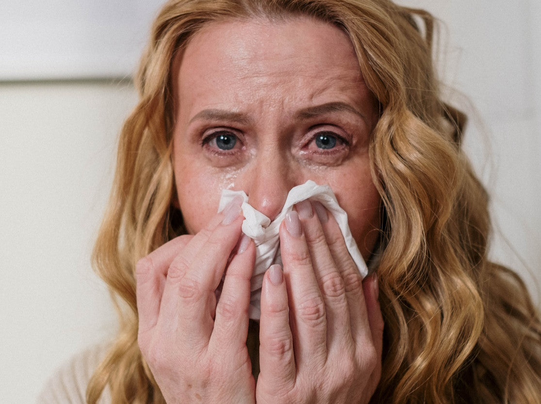 Woman with red eyes wiping nose